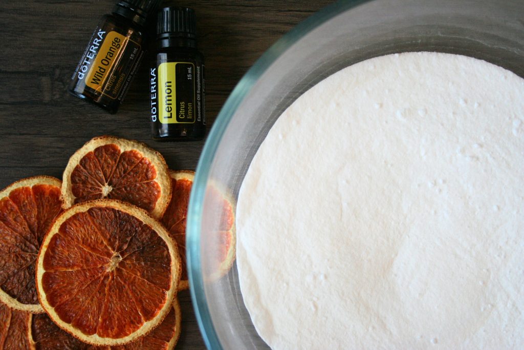 baking soda and salt mixed together in a bowl with dehydrated fruit and essential oils on the side
