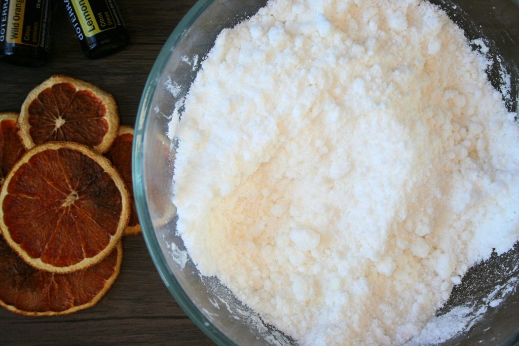 baking soda and sea sale and castile soap mixed together in a bowl with dehydrated fruit and essential oils on the side